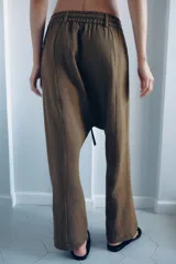 Pantalón tipo baggy de tiro bajo, confeccionado en mezcla de lino. Presenta cintura elástica con cordón ajustable, cierre frontal con botones y falsos bolsillos de vivo en los laterales.