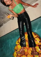 Pantalón de cuero color marrón con estampado abstracto, corte acampanado y abertura en el ruedo.