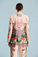 Saco de mujer Natalia Antolin con silueta estructurada, solapa chal y un llamativo estampado floral y botánico en tonos verdes, rojos y blancos sobre base rosada.
