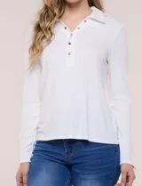 Remera de silueta al cuerpo de tejido de punto acanalado blanco, con cuello polo, abertura frontal con botones dorados y mangas largas con puños abotonados.