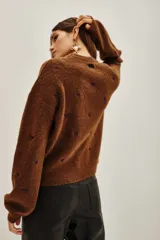 Sweater de punto color marrón con diseño de pequeños corazones bordados en color violeta, de corte holgado y manga larga.