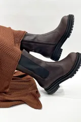 Bota de cuero color marrón chocolate, con elásticos laterales negros, cierre lateral y suela track color negro.