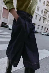 Bermuda de tiro alto en denim azul oscuro, corte ancho tipo culotte, con pinzas delanteras y pespuntes en color caramelo.