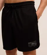 Bermuda deportiva de baloncesto color negro, confeccionada en tejido de malla texturizada, con cintura elástica, cordón ajustable y bolsillos laterales. Presenta una etiqueta pequeña aplicada en el bajo izquierdo.