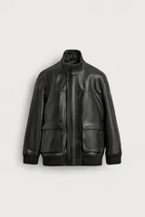 Cazadora de cuero color negro, de corte relaxed fit y estilo aviador. Cuenta con cuello alto, cierre frontal con cremallera oculta por solapa con botones a presión, grandes bolsillos de parche con solapa en la parte delantera y puños y dobladillo de canalé elástico.