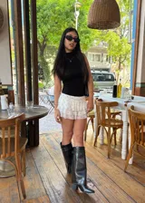 Botas de caña alta color negro, con diseño de estilo western y punta fina. Presentan doble correa superior con hebillas metálicas y detalles de tachas, además de una abertura lateral en la caña y taco cuadrado.