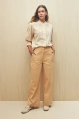 Pantalón de vestir color beige, de corte wide leg y tiro alto, con bolsillos laterales y traseros.