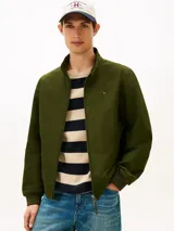 Campera tipo Harrington de Tommy Hilfiger en color verde militar, con cuello alto, cierre frontal de cremallera y bolsillos laterales. Cuenta con elásticos en puños y dobladillo, y el logo bordado en el pecho.