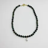 Collar de cuentas de ágata musgo de 8 mm con nudos de hilo verde como separadores. Incluye un dije central de perla natural y cierre de mosquetón con baño de oro.