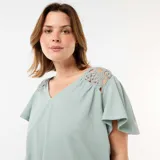 Camiseta color verde menta de tejido crepé con escote en V y mangas cortas acampanadas. Presenta detalles de encaje de macramé en los hombros.