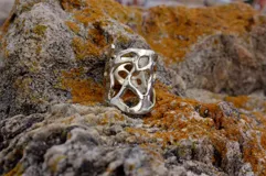 Anillo ancho de diseño orgánico y calado, con apariencia de red o magma solidificado.