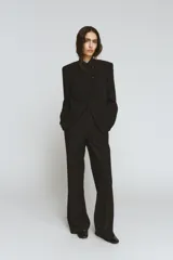 Blazer de cuello alto y manga larga con cierre frontal de botones metálicos en relieve. Presenta aberturas en los puños con botones y falsos bolsillos de vivo en el delantero.