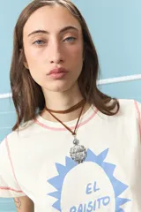 Collar de cordón marrón con dije de escudo plateado con detalles grabados y sol en la parte superior.