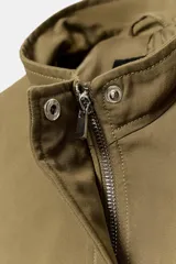 Cazadora entallada Zara color verde militar, con cuello alto, manga larga y bajo acabado en peplum. Cuenta con cierre frontal oculto con cremallera y botones a presión.
