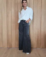 Jean de corte wide leg en color gris oscuro, con tiro medio, cierre frontal con botón y bolsillos laterales y traseros.