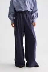 Pantalón azul marino de tiro medio con sutiles rayas verticales blancas, cintura elastizada, perneras amplias y bolsillos tipo ojal.