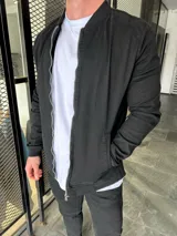 Campera bomber negra de gabardina con cierre frontal y bolsillos laterales.