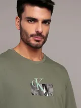 Remera de algodón de corte regular, color verde militar, con cuello redondo y estampado frontal con el logo de Calvin Klein dentro de un recuadro brillante.