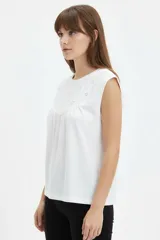 Musculosa de algodón blanca con cuello redondo y detalle de bordado en el canesú delantero.