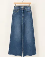 Pantalón de denim estilo wide leg, color beige, con diseño de tiro alto y ruedo desflecado.