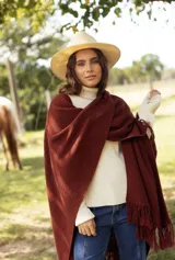 Ruana de lana merino color marrón, con diseño de tejido de punto texturizado y terminaciones con flecos en los bordes.