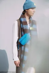 Bandolera mini color amarillo pastel, con bolsillo frontal y correa de cinta negra regulable.