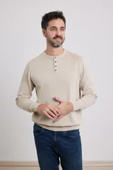 Sweater de punto color beige, con cuello redondo y tapeta con tres botones.