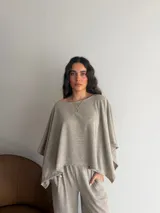 Conjunto de dos piezas de lanilla en color gris melange, compuesto por una blusa de corte amplio con mangas murciélago y escote bote, y un pantalón recto con bolsillos laterales.