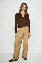 Pantalón de tiro bajo con diseño cruzado tipo pareo en el frente y lazo ajustable. Presenta pernera recta y cierre lateral con cremallera oculta.