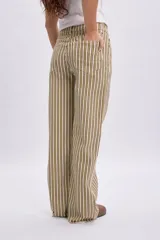 Pantalón de corte recto y holgado con estampa a rayas verticales en tonos verde, beige y marrón. Cuenta con cintura elástica y bolsillos laterales.
