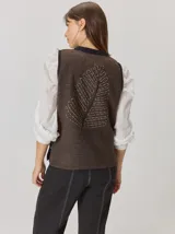 Chaleco de diseño original con frente en color negro y espalda en color marrón con textura de espiga. Presenta un maxi bordado en la espalda que representa una hoja de ciprés calvo.