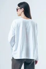 Remera de manga larga con corte oversize, confeccionada en algodón de color blanco, con cuello redondo y diseño minimalista.