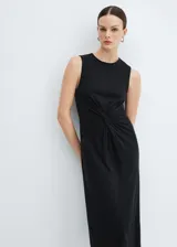 Vestido midi de algodón color negro, con cuello redondo, sin mangas y diseño recto. Presenta un detalle de nudo en la cintura que genera un efecto drapeado.