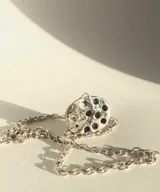 Collar plateado con dije irregular con incrustaciones de strass azules y transparentes.