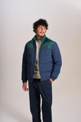 Campera puffer con diseño bicolor, cuerpo en azul marino y canesú superior en verde oscuro. Presenta cuello alto, cierre frontal completo y puños elásticos.