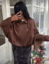 Campera tipo bomber de gamuza en color marrón, con cuello clásico, mangas largas amplias y ruedo elástico que genera un efecto fruncido.