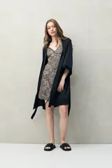 Bata de pijama negra de tejido satinado con leve elasticidad, silueta fluida y estilo envolvente. Presenta diseño cruzado con lazo regulable en la cintura y mangas amplias.