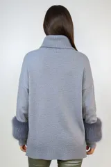 Polerón de punto color gris con cuello alto y puños con detalle de piel sintética en tono más oscuro. Presenta un corte holgado y diseño clásico.