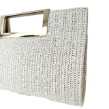 Sobre de rafia sintética color beige con textura trenzada y asa metálica dorada. Incluye correa desmontable para usar al hombro o cruzado.