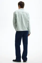 Camisa de manga larga de algodón Oxford con patrón de rayas verticales en color verde y blanco, cuello americano, cierre frontal de botones y un bolsillo aplicado en el pecho.