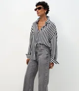 Pantalón wide leg de tiro alto confeccionado en denim de algodón. Presenta un diseño con friso vertical en el frente, cierre de botón y cremallera, trabillas en la cintura y bolsillos funcionales en la parte delantera y trasera.