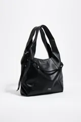 Bolso grande de cuero negro tipo shopper, modelo Paper de Bimba y Lola, con doble asa de hombro, detalles de cordones trenzados decorativos y el logo impreso en plateado en la parte inferior.