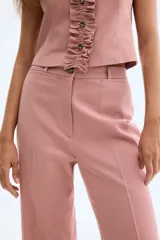 Pantalón de corte ajustado en sarga de mezcla de algodón y lino, color rosado. Modelo de tiro alto con cierre y botón, bolsillos insertados adelante y bolsillos decorativos atrás. Piernas acampanadas con raya adelante y atrás.