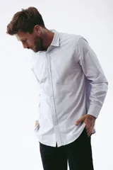 Camisa celeste a rayas verticales blancas, de corte clásico, manga larga y cuello abotonado.