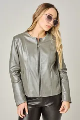 Campera de cuero ovino color gris verdoso, con cuello redondo a la base y cierre frontal completo. Presenta costuras verticales decorativas en el frente y bolsillos laterales con cierre.