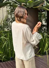 Camisa color crudo con cuello mao y volados frontales. De manga larga con puños fruncidos.