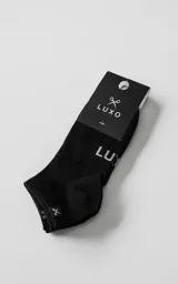 Soquetes negros de algodón con spandex, de corte bajo. Presentan el logo de la marca tejido en la planta del pie y una pequeña etiqueta con el logo de la tijera en el borde superior.