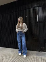 Pantalón de jean azul de corte recto y tiro alto, con detalle de tachas metálicas en los bolsillos delanteros y cierre frontal con botón.