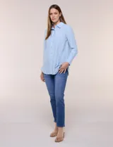 Camisa de calce relajado color celeste, confeccionada en tejido de textura suave y fluida. Presenta cuello camisero y abotonadura frontal, mangas largas con puño ancho y ruedo curvo.