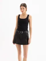 Minifalda de cuero ovino graneado negro, de tiro medio-alto y silueta evasé, con forrería interna y cinturón integrado con hebilla y ojalillos metálicos.
